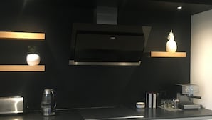 Une cuisine moderne dotée d’un plan de travail noir, de meubles blancs et d’une machine à expresso intégrée.
