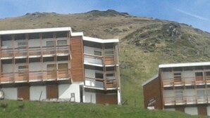 A modern building with a flat roof, multiple windows, and a wooden facade. - La Mongie - Apartment T2 for 5 people with balcony - Résidence Béro Bisto (Bagnères-De-Bigorre)