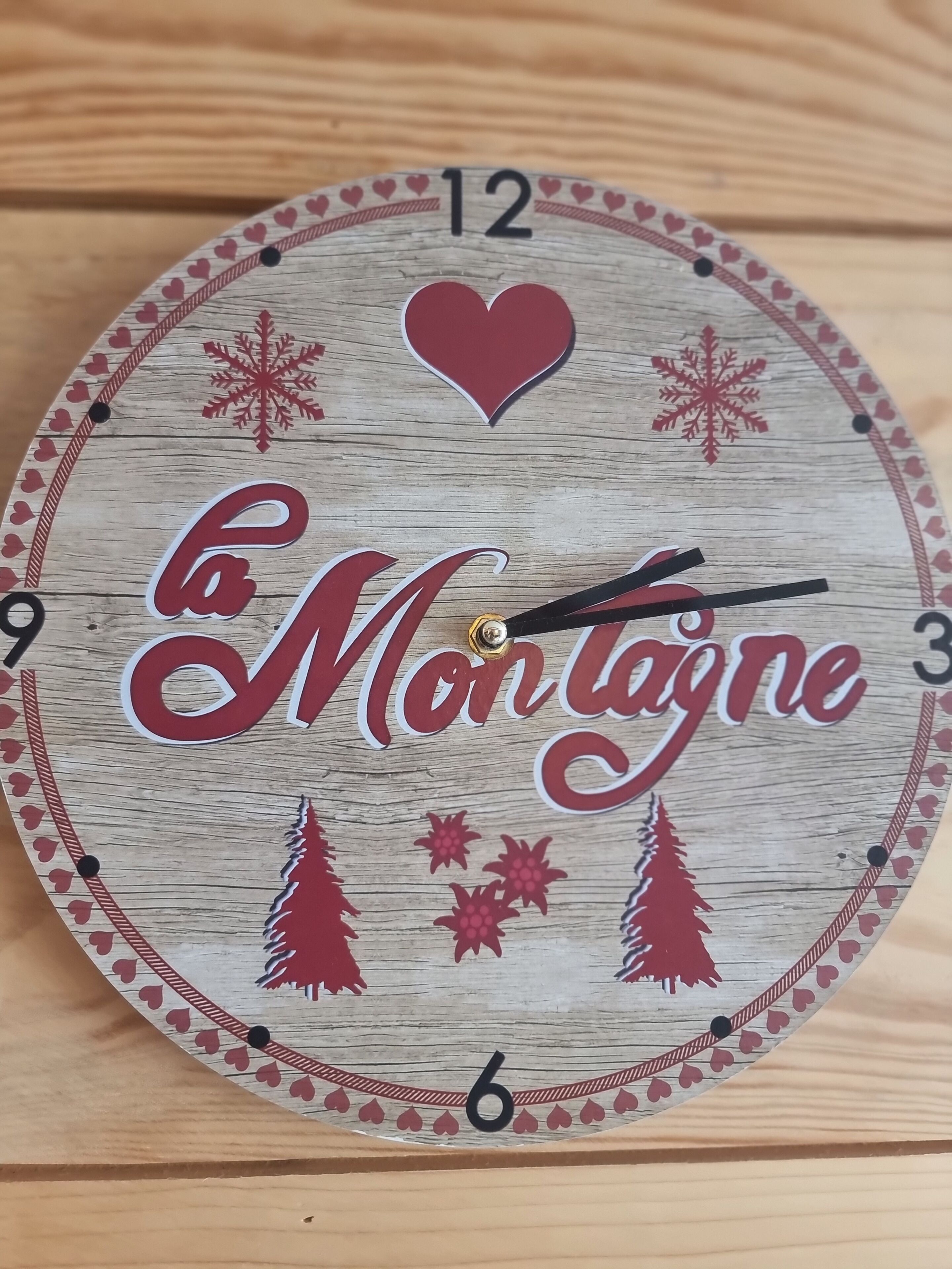 A clock with the text "la Montagne" and decorative elements like trees and snowflakes.