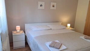 A neatly arranged bedroom with a bed, two bedside tables, and two wall-mounted lamps. - Charming 2-Bedroom Apartment for Four, With Parking (Pula)