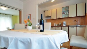 A dining area with a table set for two, a bottle of wine, and a vase of flowers. - Charming 2-Bedroom Apartment for Four, With Parking (Pula)