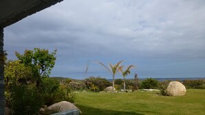 A patio area with a stone wall, a grassy lawn, and a view of the sea. -  MODERN VILLA 10 PERONNES SWIMMING POOL 10MN FROM THE BEACH AND SPERONE GOLF VIEW  (Bonifacio)