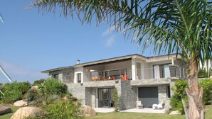 A modern two-story house with a stone facade, large windows, and a balcony with outdoor seating. -  MODERN VILLA 10 PERONNES SWIMMING POOL 10MN FROM THE BEACH AND SPERONE GOLF VIEW  (Bonifacio)