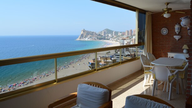 A balcony with a view of the beach and ocean, a table with chairs, and a ceiling fan. - Apartment facing the sea. In the center of the Poniente Beach. WIRELESS. Swimming pool (Benidorm)
