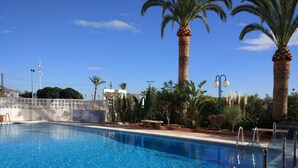 A clear blue swimming pool surrounded by palm trees and a white fence. - Apartment facing the sea. In the center of the Poniente Beach. WIRELESS. Swimming pool (Benidorm)