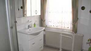 A bathroom with a white sink, mirror, and radiator. There is a green rug on the floor.