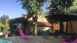 Una terraza de madera con sillones de descanso y una piscina.