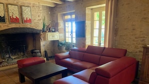 Una sala de estar con un sofá de cuero rojo, una mesa de centro oscura y una chimenea de piedra.