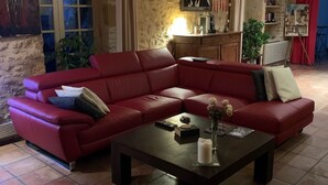 Una sala de estar con un sofá modular rojo, una mesa de centro y una pared de piedra.