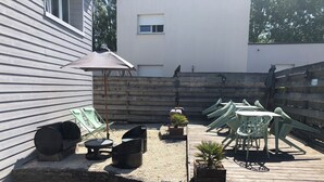 Un espace patio aménagé avec du mobilier d’extérieur, un barbecue et une terrasse en bois.