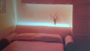 Ein Zimmer mit einem Bett, einer Vase mit getrockneten Blumen und Holzschränken.