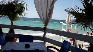 Ein Restaurant direkt am Strand mit Außenbereich, Blick auf das Meer und einem Rettungsturm im Hintergrund.