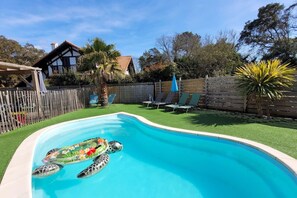 Relax by the pool surrounded by lush greenery and comfortable lounge chairs.