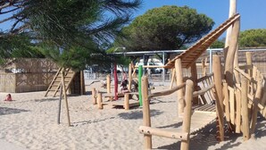 Un parque infantil con estructuras de madera y suelo de arena.