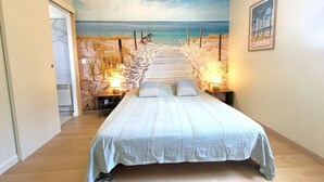 Un dormitorio con un mural al estilo playero, una cama de madera y lámparas de noche.