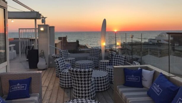 Una terraza con mobiliario exterior y vistas de la puesta de sol sobre el agua.
