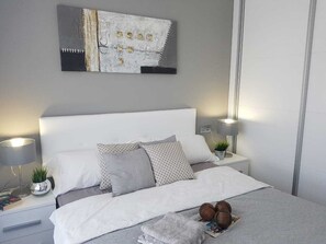 A neatly arranged bedroom with a large bed, two bedside tables with lamps, and a wall-mounted artwork.