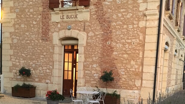A stone building with a sign reading "LE BUCUE".