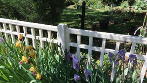 A garden with a white picket fence, various plants, and a pathway.