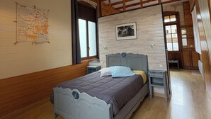 A bedroom with a wooden ceiling, a bed with a headboard, a nightstand, a map on the wall, and a window.