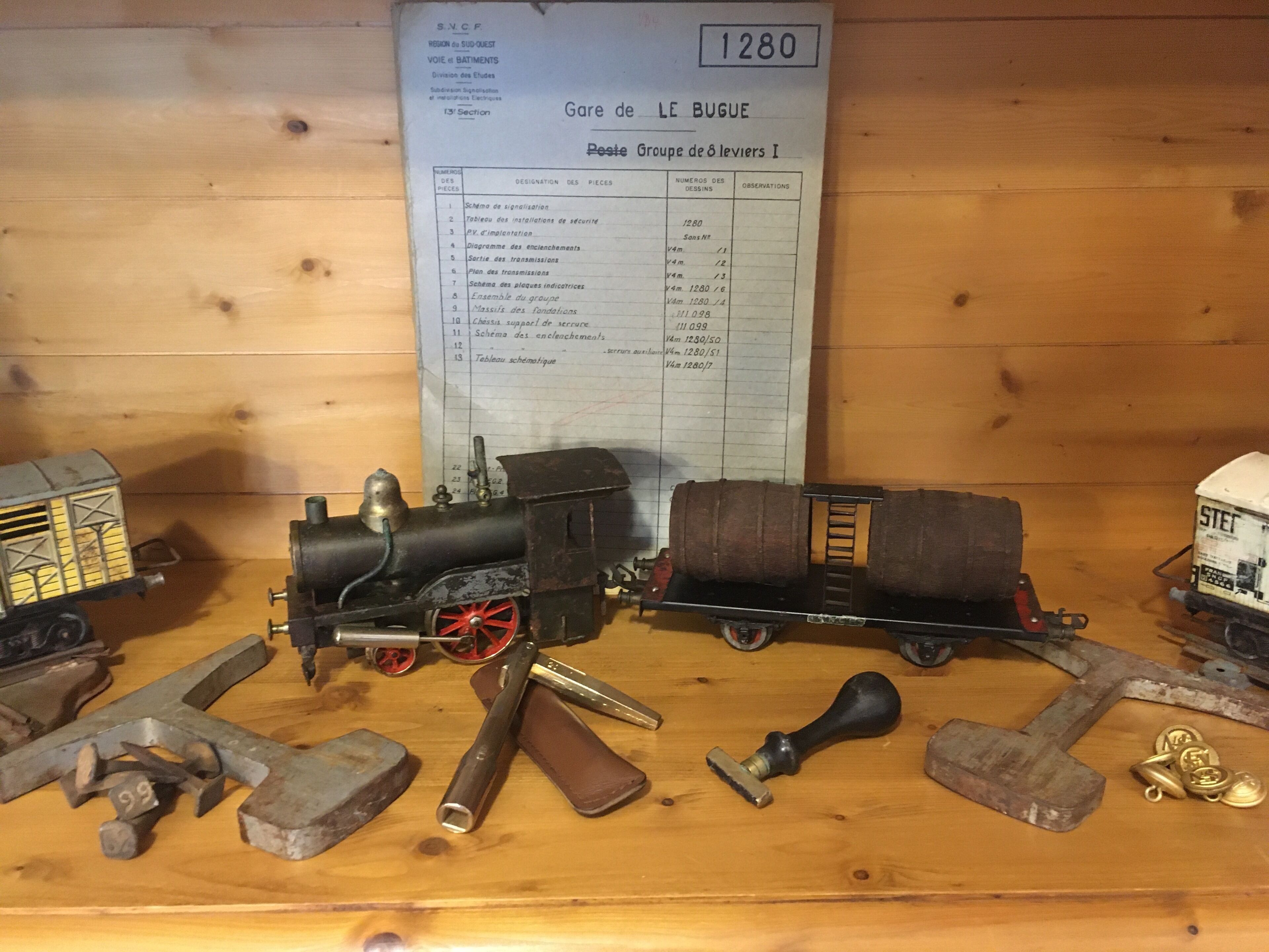 Un présentoir en bois avec des maquettes de trains et des outils anciens.