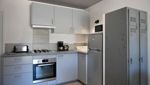 Une cuisine moderne avec des armoires blanches, un four encastré, un four à micro-ondes et un réfrigérateur en acier inoxydable.