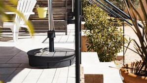 Une terrasse avec des meubles d’extérieur, un mur en bois et des plantes en pot.
