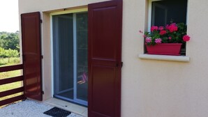 A building entrance with a sliding glass door and a small window with a flower box. - Bed and Breakfast Le Chêne (Mauzens et Miremont)
