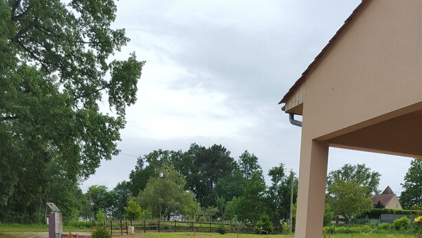 A garden with a variety of flowers and plants, a stone wall, and a building in the background. - Bed and Breakfast Le Chêne (Mauzens et Miremont)