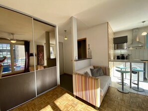 A compact living space with a sofa, a dining area, and a kitchenette.