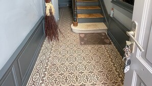 Eine Treppe mit einem gemusterten Boden, ein Besen und ein an der Wand befestigtes Schild.