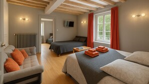 Ein Schlafzimmer mit einem Bett, einer Couch, einem Fernseher und einem Fenster mit Vorhängen.