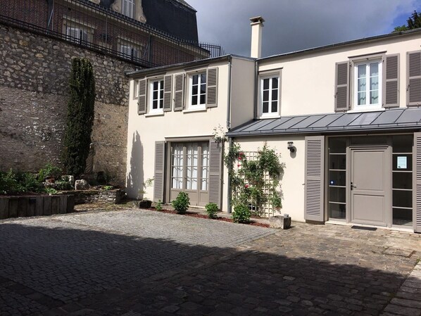 A two-story building with a stone facade, shutters, and a paved courtyard. - 3-room apartment with parking in downtown Chartres—Maison de l'Octroi (Chartres)