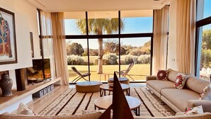 Un salón moderno con un ventanal grande, un sofá, una mesa de centro y una maqueta de un velero.