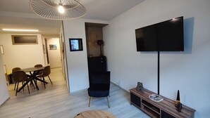 Ein modernes Wohnzimmer mit einem Flachbildfernseher, einem Essbereich mit Tisch und Stühlen sowie einer Treppe zu einem anderen Raum.