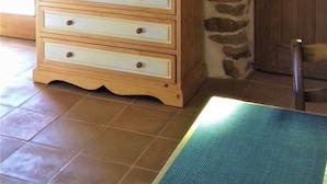 Ein Zimmer mit Steinwand, einem Holzkasten mit Schubladen, einem flachbildfernseher darüber montiert und einer Holztür.