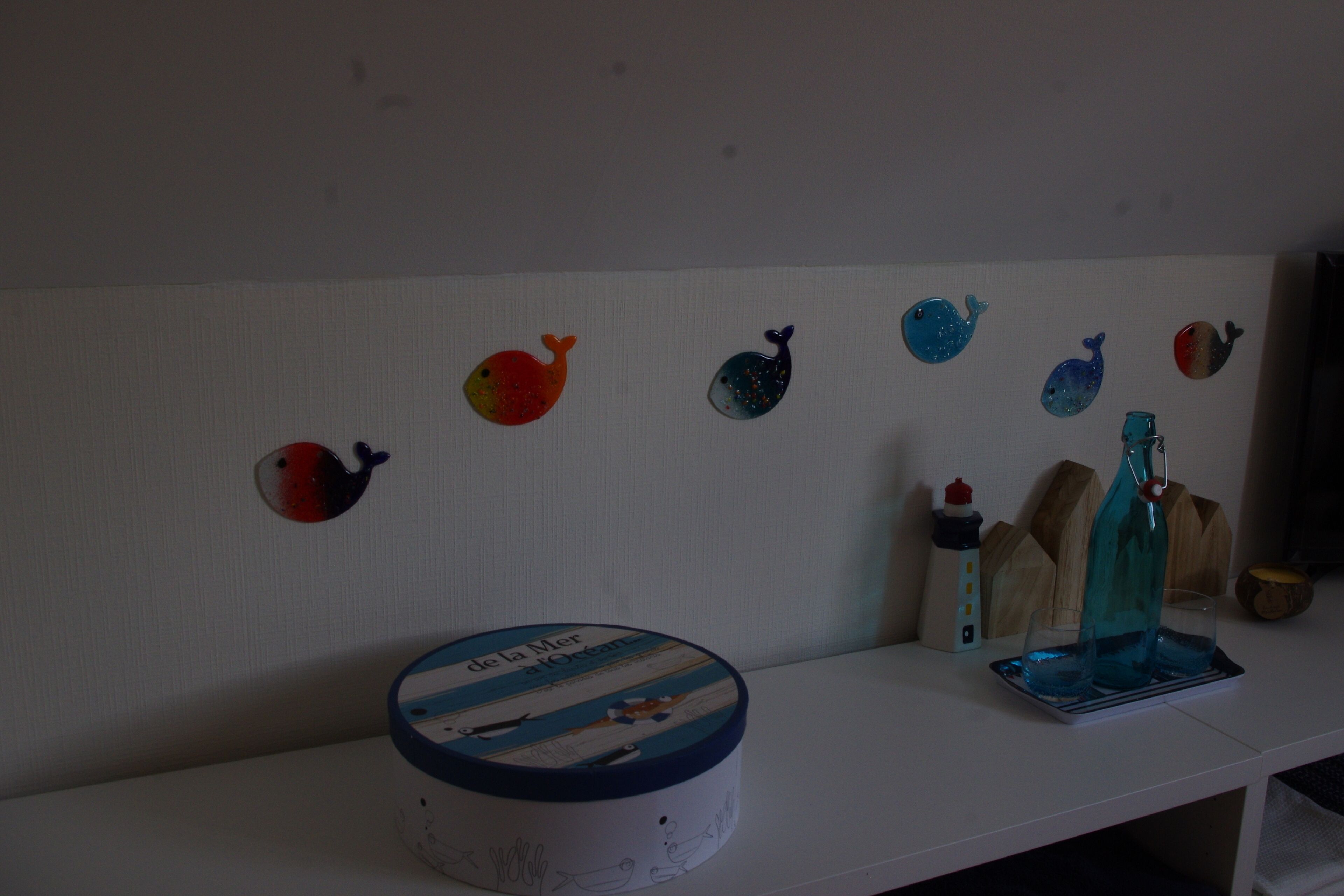 A white shelf with a round container labeled "de la Mer," a blue bottle, and a glass set.