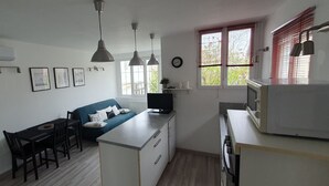 Una cocina compacta con comedor, un banco empotrado, luces colgantes y un ventanal con persianas.
