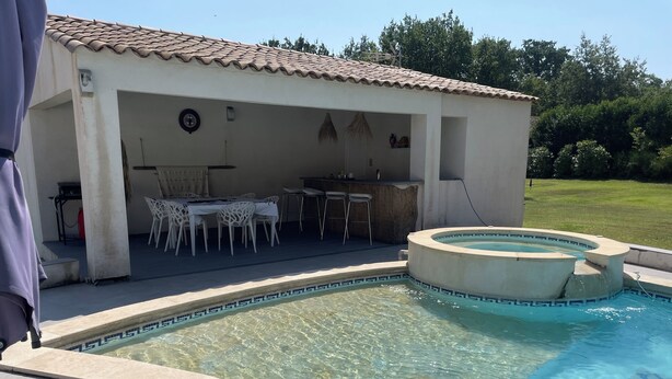 A swimming pool with a tiled deck, a covered outdoor seating area with tables and chairs, and a bar. - Pretty little independent house  (Dions)