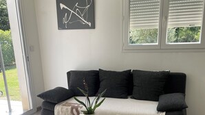 A modern living room with a grey sofa, a white coffee table, and a potted plant. - Pretty little independent house  (Dions)