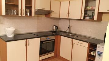 A compact kitchen with a black countertop, stainless steel appliances, and wooden cabinets.
