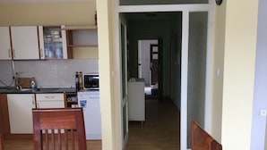 Una cocina con armarios, microondas y refrigerador. Una silla de madera está en primer plano.