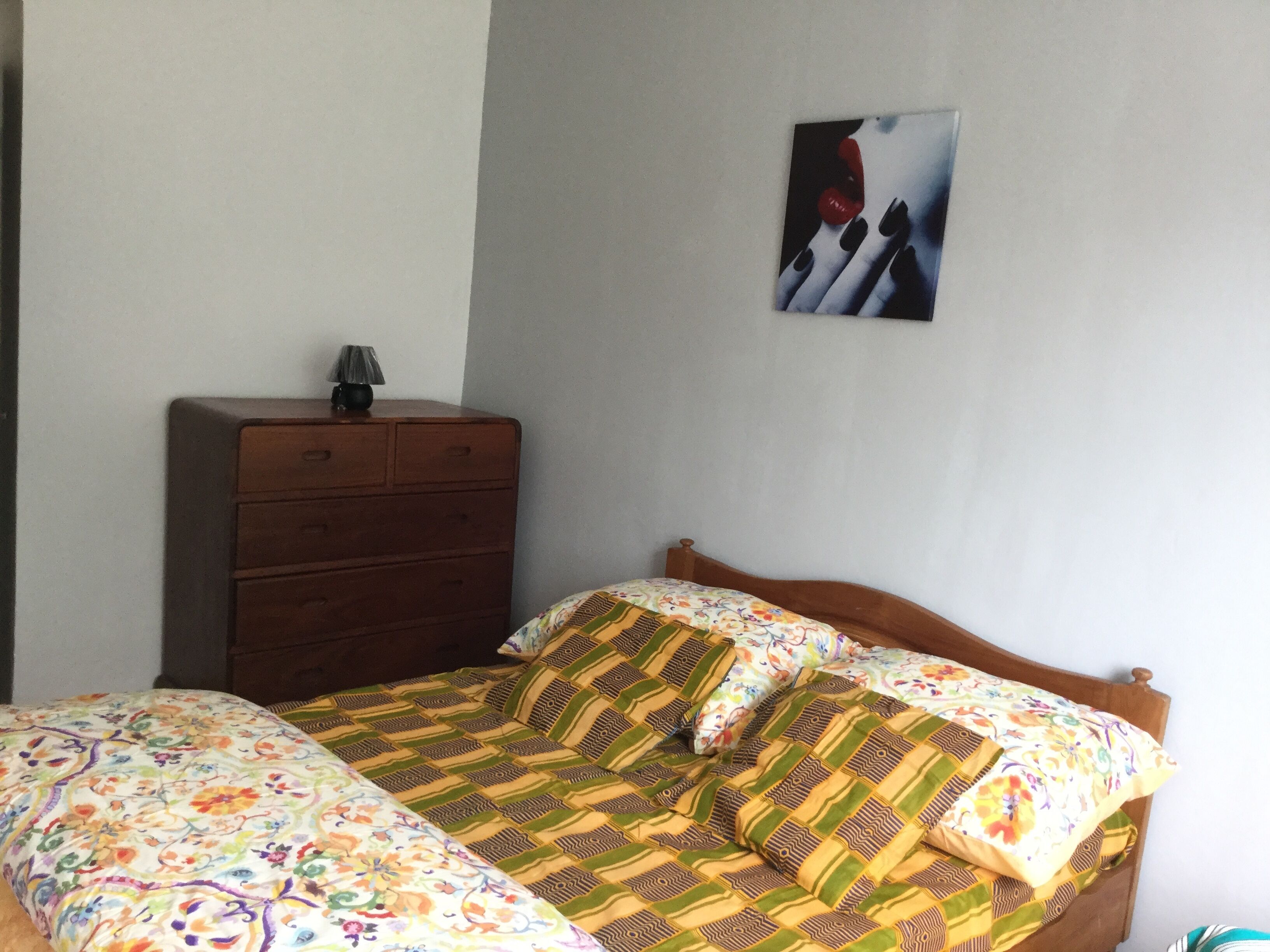 A bedroom with a bed, a dresser, and a wall-mounted picture.