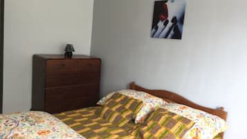 A bedroom with a bed, a dresser, and a wall-mounted picture.