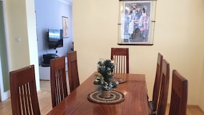 Un comedor con una mesa de madera, seis sillas y un pequeño árbol de Navidad.