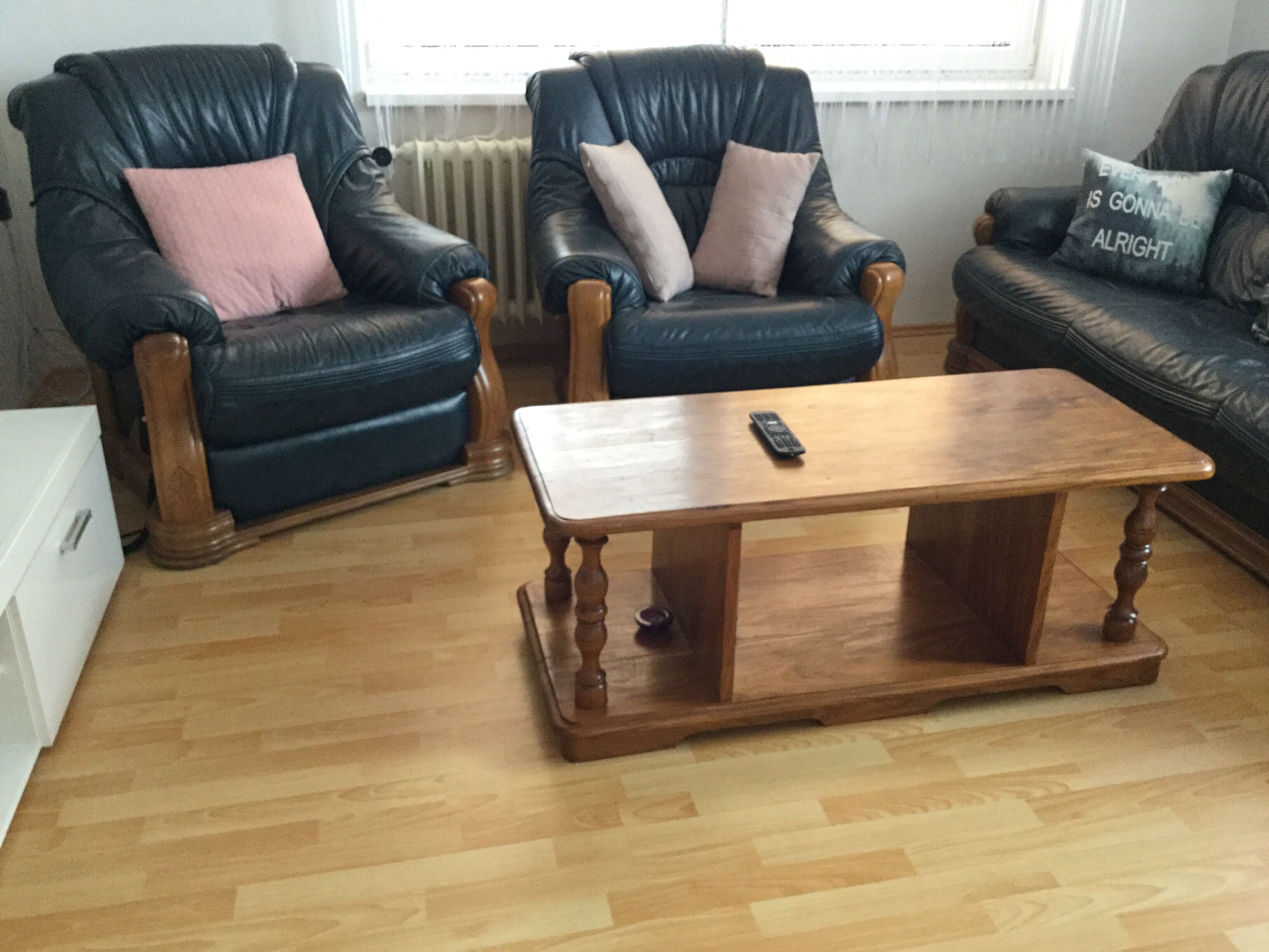 A living room with two leather armchairs, a wooden coffee table, and a blue sofa.