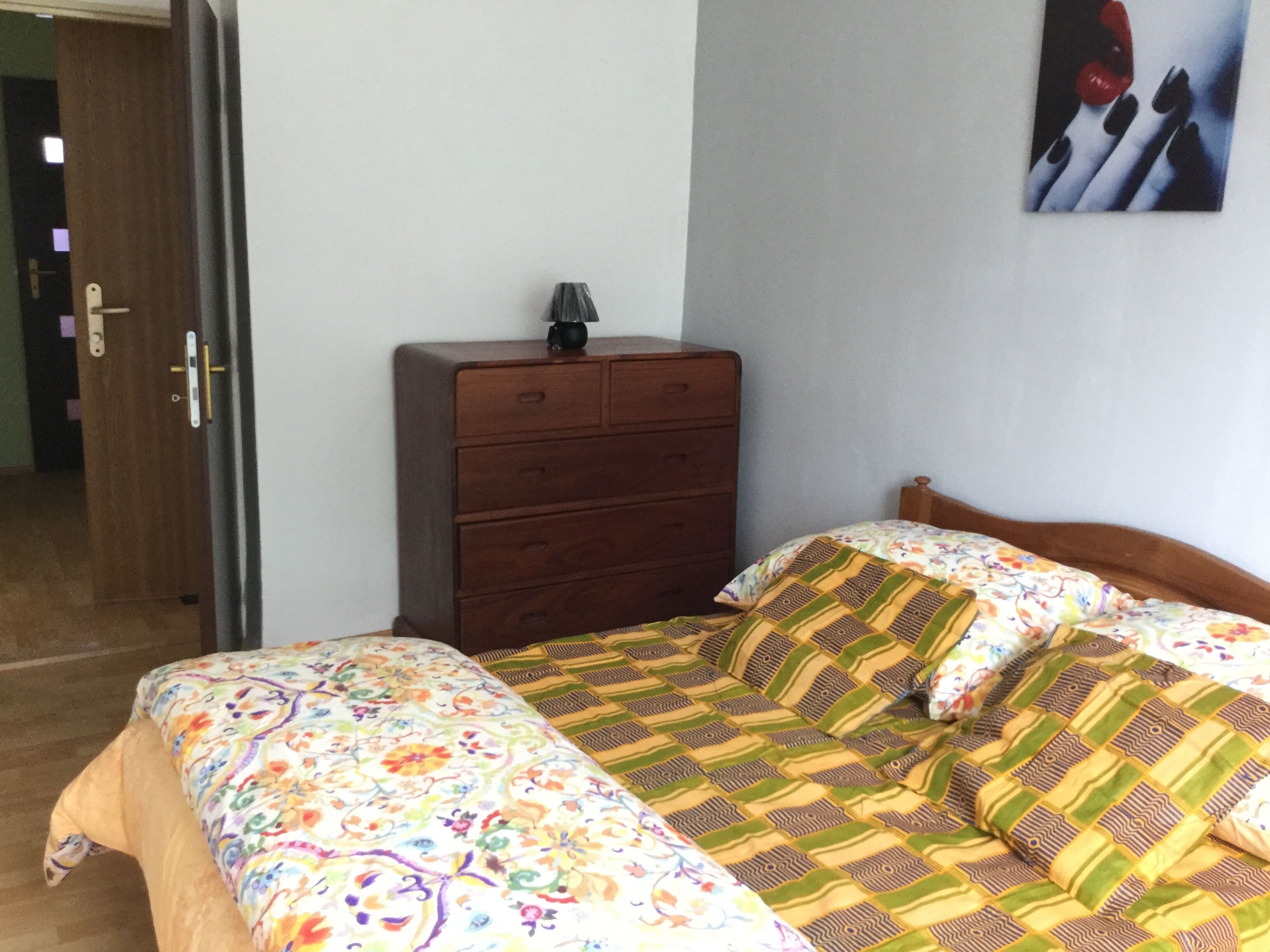 A bedroom with a bed, a dresser, and a door.