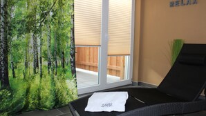 A spa room with a relaxation area, a sliding glass door leading to an outdoor deck, and a 'RELAX' sign on the wall. - Modern apartment with terrace and use of sauna (Burgbernheim)
