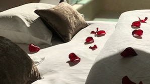 A hotel room with a bed, pillows, and rose petals on the bed. - Véronique luxuriou's penthouse (Eilat)