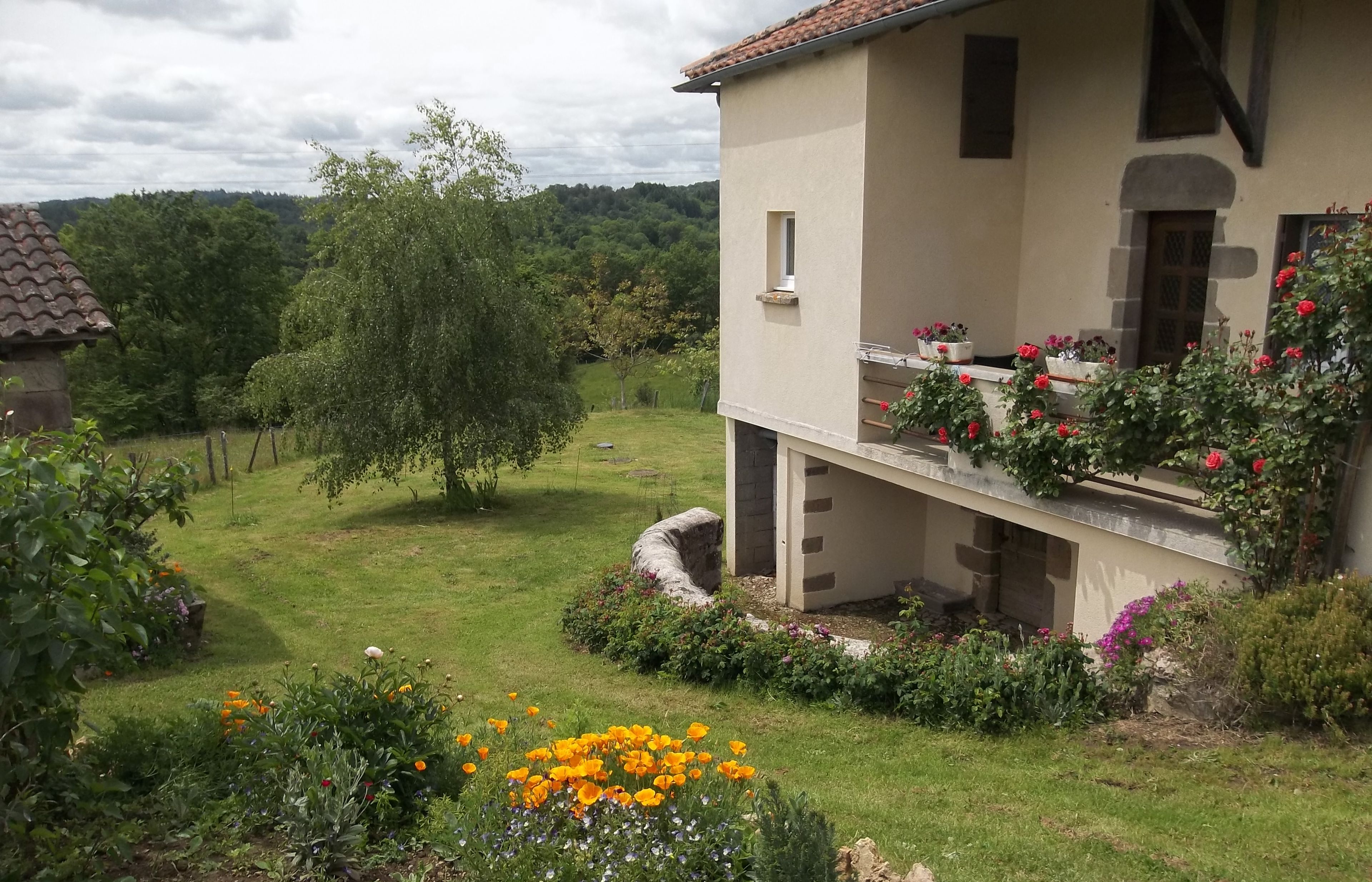 Une maison avec un jardin, un balcon orné de fleurs et un cachet indiquant la date.